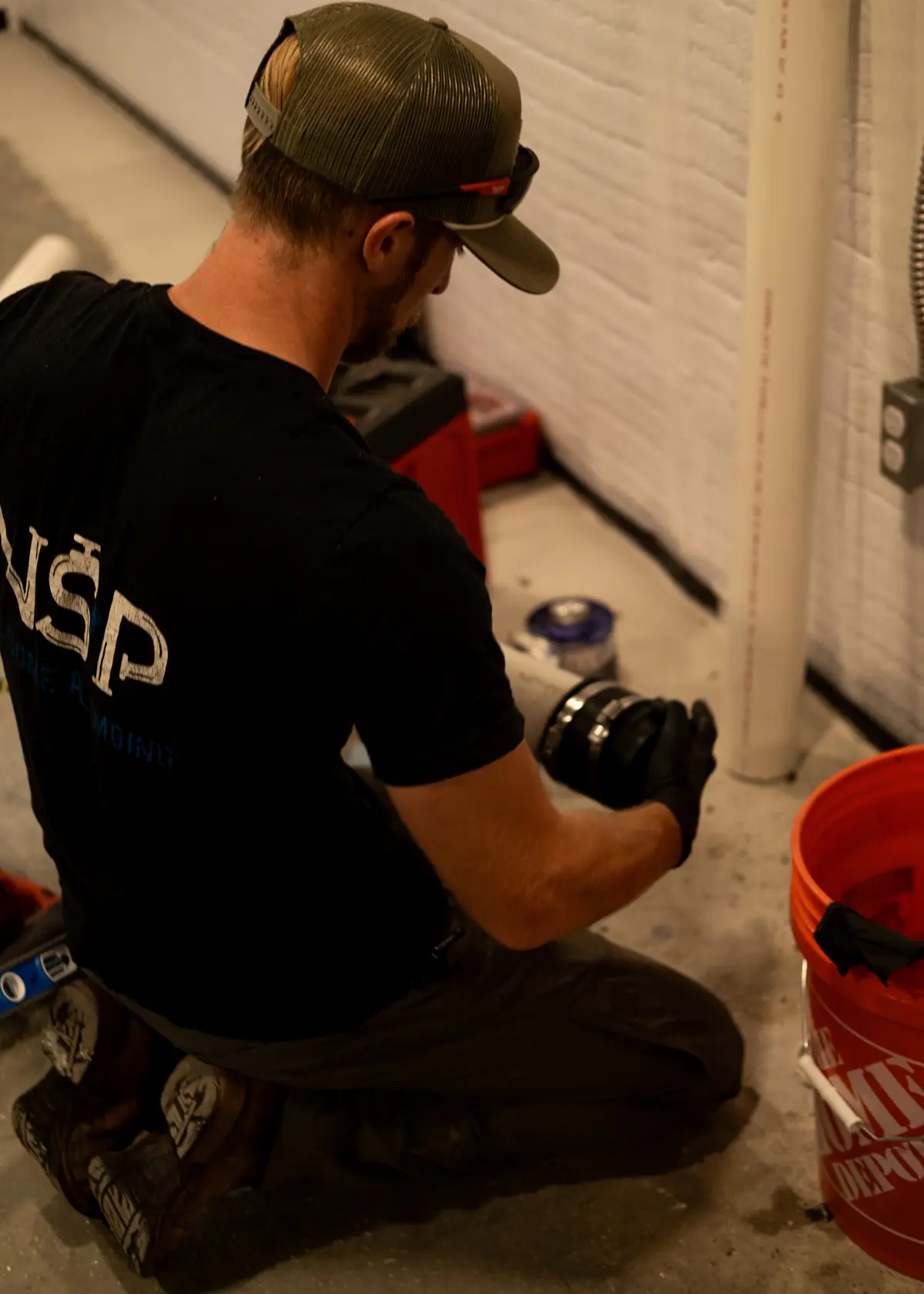 NSP Plumbing plumber fitting a rubber coupling during a basement drain stack replacement