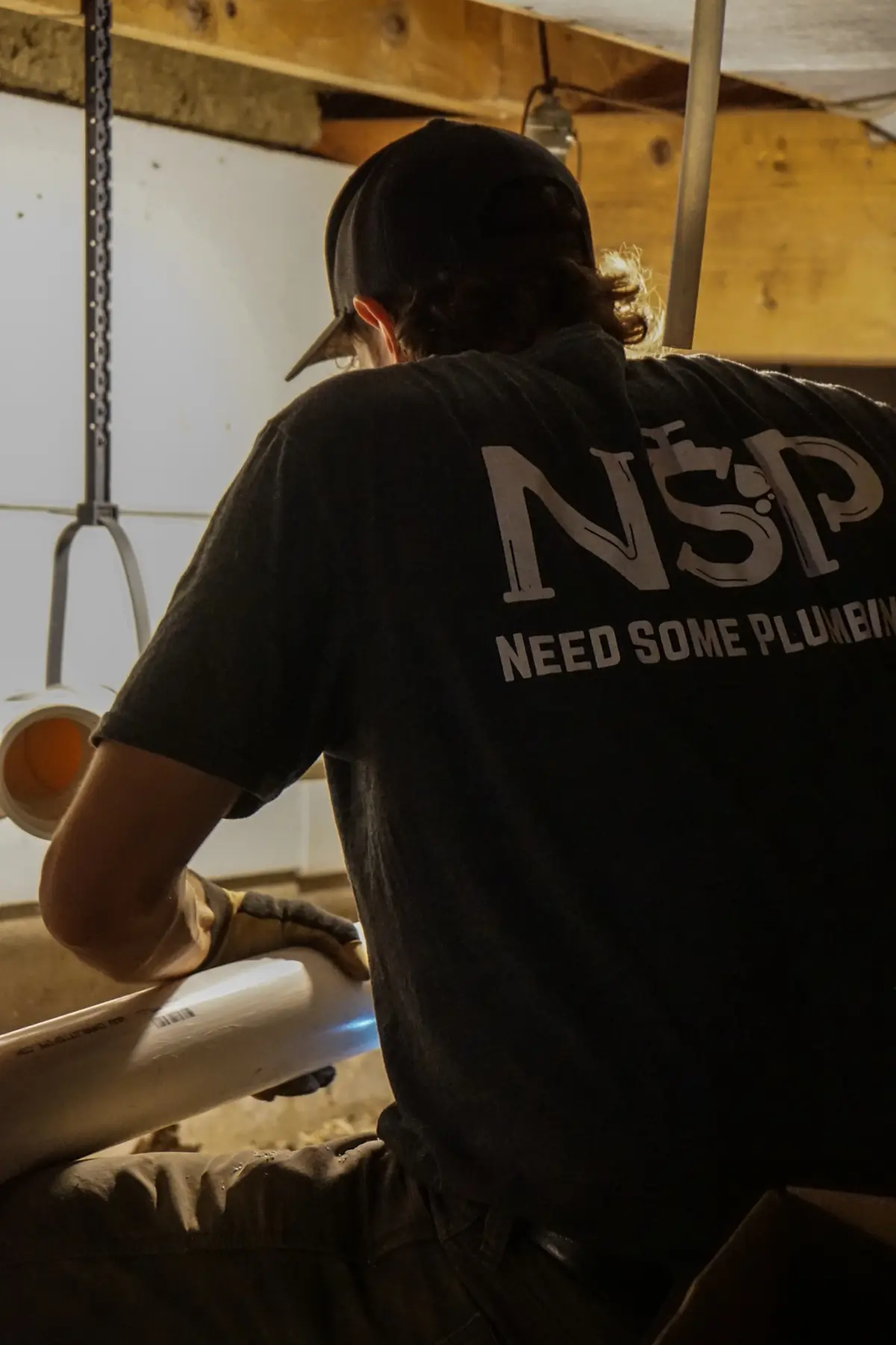 NSP Plumbing plumber fitting new PVC pipe in a crawlspace during a repipe